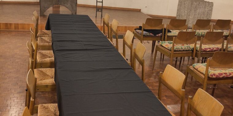 eine Kirche mit einem Kreuz und Altar, davor Tisch, schwarz bezogen